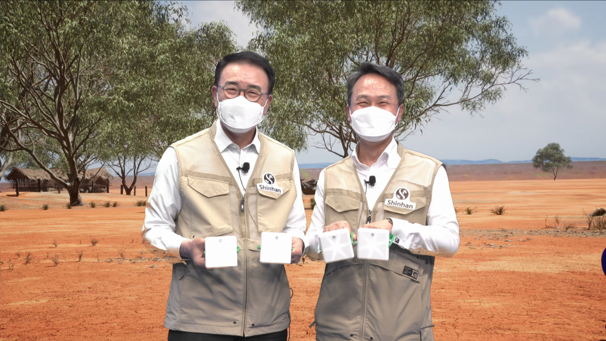 ▲조용병 신한금융그룹 회장(사진 왼쪽)과 신한은행 진옥동 은행장이 15일 신한은행 디지털 방송국에 구축한 AR 스튜디오에서 증강현실을 활용해 구현한 아프리카 마을 현장을 배경으로 기념 촬영을 하고 있다. (사진제공=신한금융그룹)