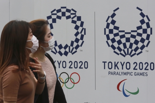 ▲16일 도쿄올림픽 로고와 올림픽 상징인 오륜기가 그려진 포스터 앞을 시민들이 지나고 있다.  (도쿄/AP연합뉴스)