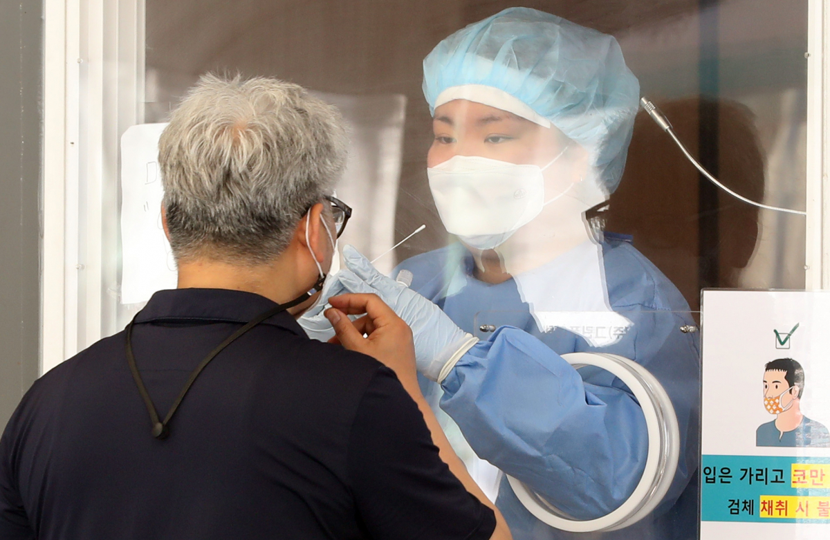 ▲13일 오전 서울 중구 서울역 앞에 마련된 코로나19 선별진료소에서 한 시민이 검체 채취를 받고 있다. (뉴시스)