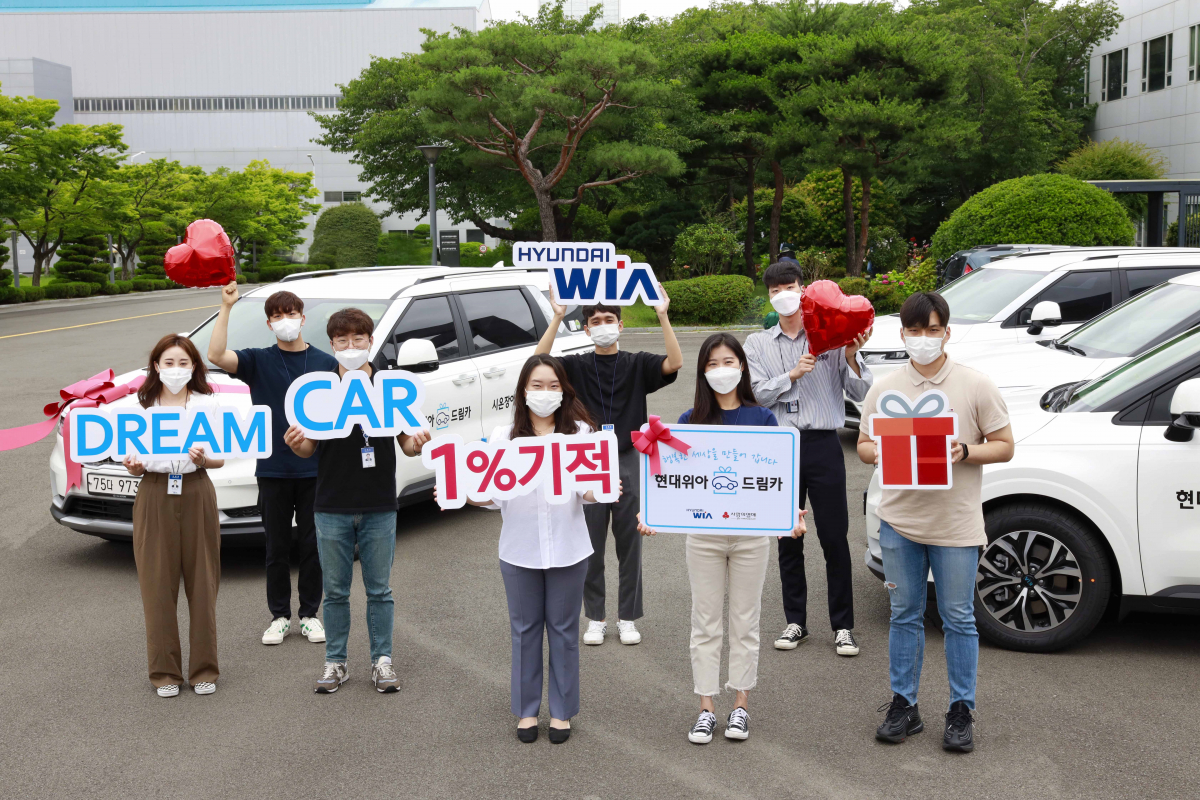 ▲현대위아 직원들이 22일 경상남도 창원시 성산구 현대위아 본사에서 지역 복지기관에 선물할 ‘현대위아 드림카’와 기념사진을 찍고 있다.  (사진제공=현대위아)