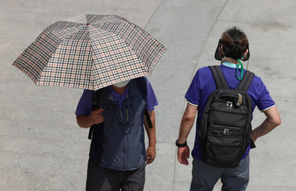 ▲무더운 날씨를 보인 9일 서울 청계천을 찾은 시민이 양산과 썬캡을 쓰고 있다.  (뉴시스)