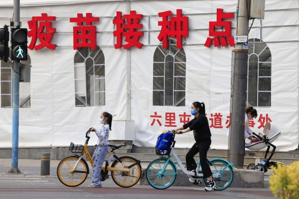 ▲중국 수도 베이징의 한 백신 접종소 인근 거리에서 자전거를 탄 여자 어린이가 횡단보도 앞에 서 있다. 베이징/AP연합뉴스
