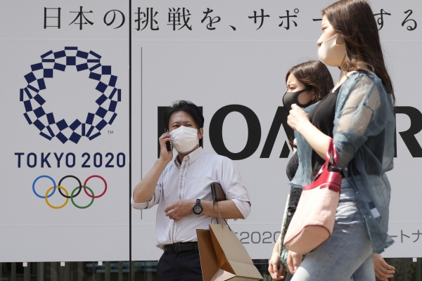 ▲ 일본 수도 도쿄에서 25일 신종 코로나바이러스 감염증(코로나19) 예방 마스크를 쓴 시민들이 도쿄올림픽 포스터 앞을 지나고 있다. 도쿄/AP연합뉴스
