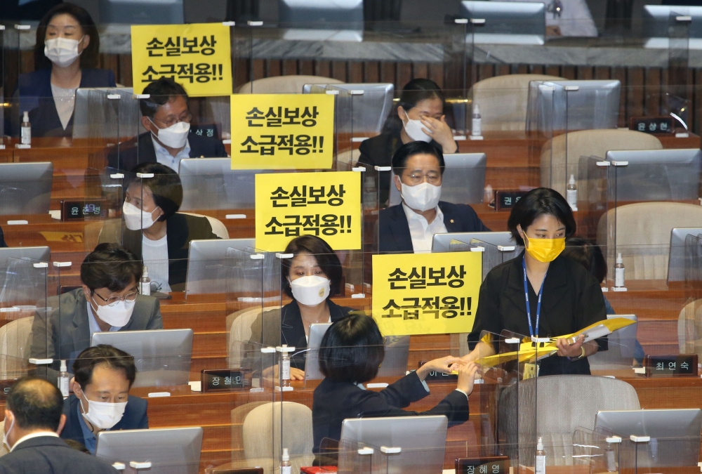 ▲정의당 류호정 의원이 1일 오후 서울 여의도 국회에서 열린 제388회국회(임시회) 제7차 본회의에서 동료의원들에게 '손실보상 소급적용'이라고 기재된 손 피켓을 나눠주고 있다. 신태현 기자 holjjak@ (이투데이DB)