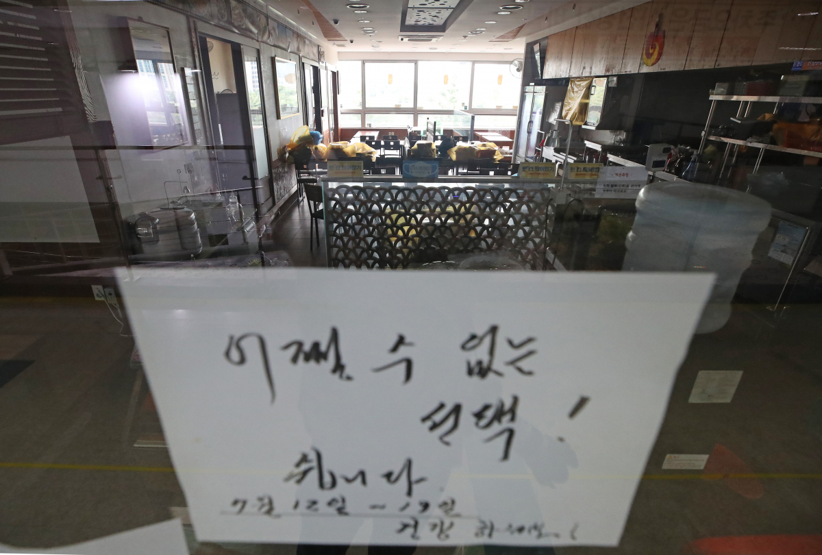 ▲수도권의 사회적 거리두기 4단계 격상 둘째 날인 13일 점심시간, 건물 내 상차림 식당들이 집단 휴점에 들어간 서울 동작구 노량진수산시장의 한 식당에 안내문이 붙어 있다. (연합뉴스)