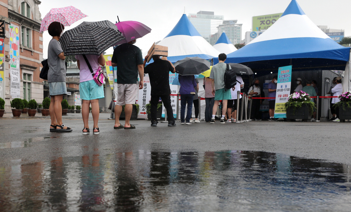 ▲소나기가 내리는 가운데 서울 중구 서울역광장에 마련된 중구 임시선별진료소에서 검사를 받으려는 시민들이 길게 줄지어 서 있다. (뉴시스)