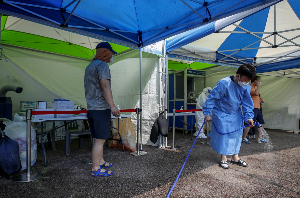 ▲폭염이 이어지고 있는 15일 오후 서울 양천구 파리공원에 설치된 찾아가는 선별진료소에서 의료진이 열을 식히기 위해 바닥에 물을 뿌리고 있다. (뉴시스)