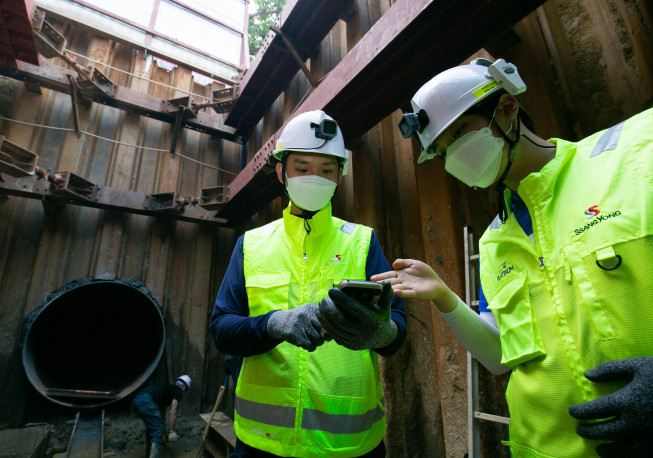 ▲쌍용건설 작업자가 액션캠과 위치태그가 장착된 스마트 안전모를 착용하고 스마트폰으로 현장을 확인하고 있다.  (자료제공=쌍용건설)