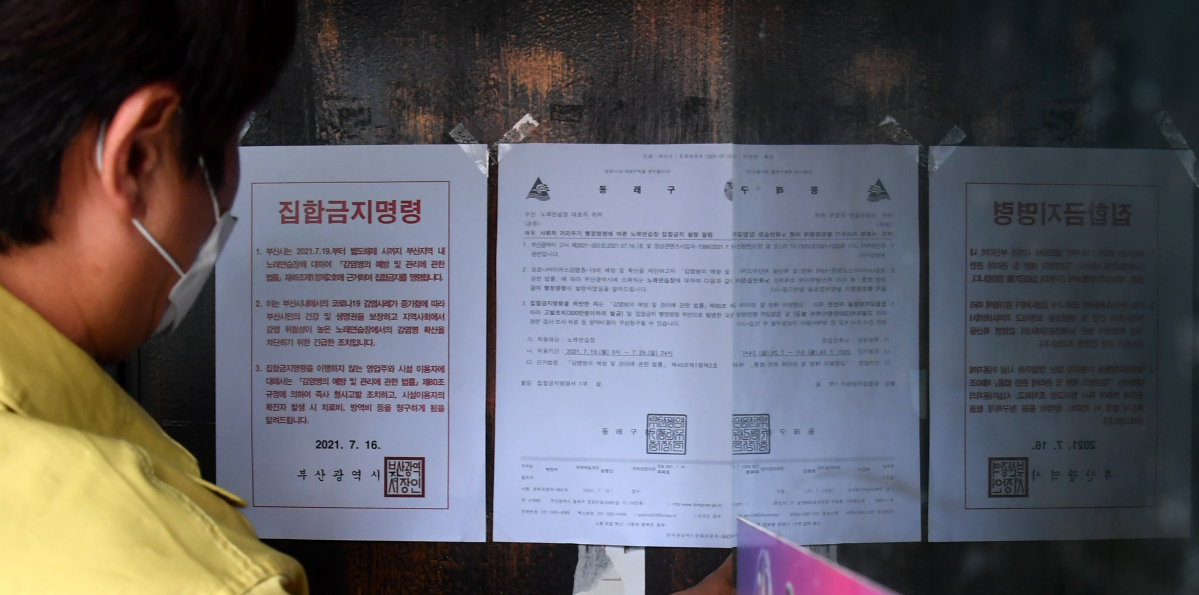 ▲19일 오후 부산 동래구청 공무원들이 노래연습장 출입구에 집합금지 행정명령문을 부착하고 있다. (뉴시스)