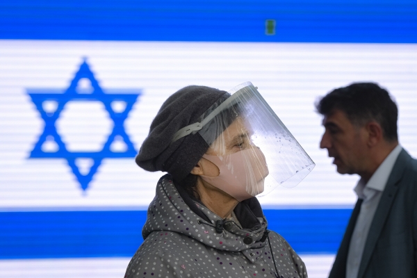 ▲마스크를 착용한 여성 뒤로 이스라엘 국기가 보인다. AP뉴시스