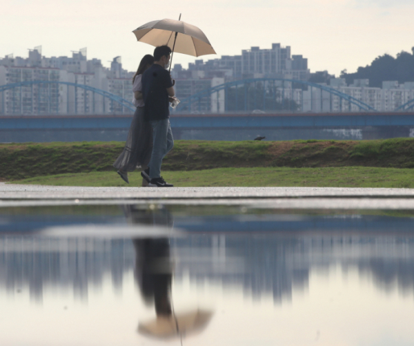 ▲폭염 속 소나기가 내린 15일 서울 서초구 반포지구 한강공원에서 시민들이 우산을 쓰고 걸어가고 있다.  (뉴시스)