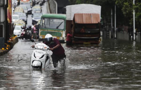 ▲인도 뭄바이에서 한 남성이 폭우로 물에 잠긴 도로 위에서 스쿠터를 끌고 가고 있다. 뭄바이/AP뉴시스 