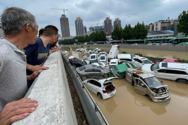 ▲지난 20일 중국 중부 허난성 성도인 정저우의 주민들이 폭우로 침수된 차들을 바라보고 있다. 이날 정저우에서는 기록적인 폭우로 지하철에 갇힌 승객 12명이 숨졌으며, 주민 10만 명이 긴급 대피했다.  (AFP연합뉴스)