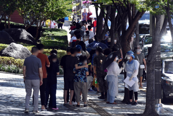 ▲부산지역 코로나19 확산세가 심상치 않은 가운데 26일 오전 부산 남구보건소 선별진료소를 찾은 시민들이 진단검사를 받기 위해 길게 줄을 선 채 차례를 기다리고 있다. 이날 해당 보건소 주변으로 검사 대기 줄이 100m 가량 이어졌다.  (뉴시스)