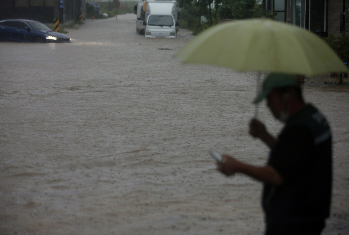 ▲18일 새벽 강원 강릉 시내에서 견인업체 직원이 물에 잠겨 멈춰 선 차량을 구조하기 위해 고심하고 있다. (연합뉴스)