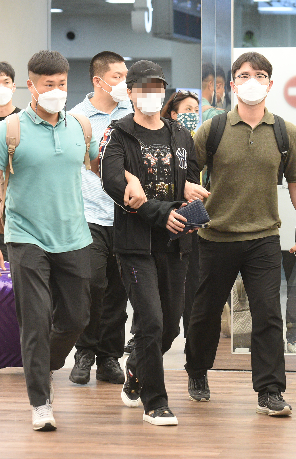 ▲18일 오후 경찰이 검정색 상하의를 입은 김씨를 제주국제공항을 통해 제주경찰청으로 압송하고 있다.  (연합뉴스)