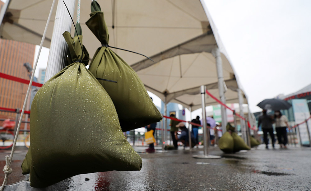 ▲제12호 태풍 '오마이스'가 북상중인 23일 오후 서울시 중구 서울역광장에 마련된 임시선별검사소 천막 기둥에는 모래주머니가 매달려 있다.  (뉴시스)