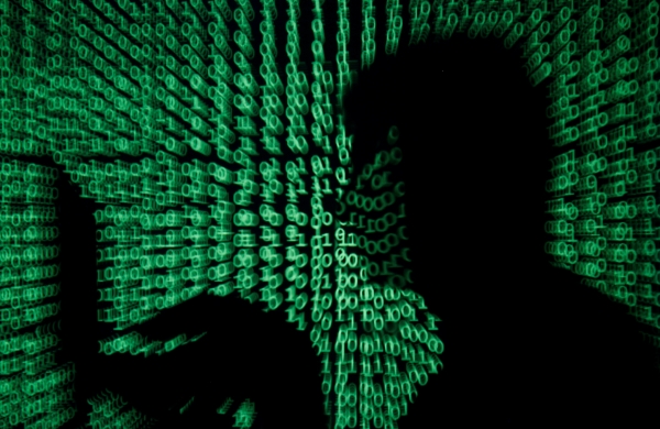▲노트북을 들고 있는 한 남성 뒤로 사이버코드가 투사되고 있다. 로이터연합뉴스
