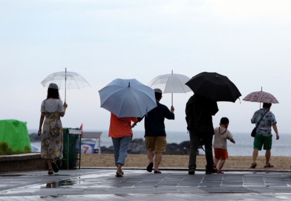 ▲피서객들이 강원 강릉시 경포해수욕장에서 우산을 쓰고 바다 쪽으로 걸어가고 있다. (뉴시스)