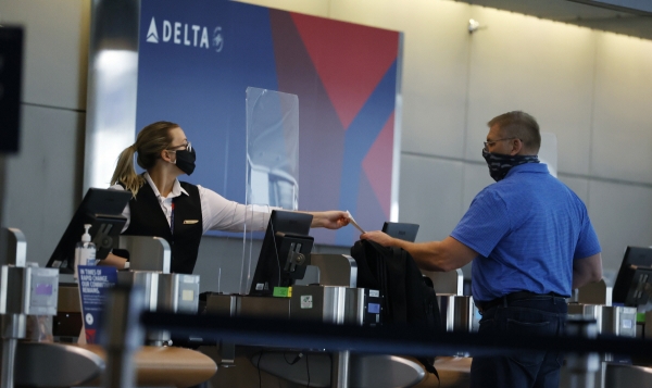 ▲미국 델타항공 직원이 마스크를 착용한 채 덴버 국제공항에서 승객에게 탑승권을 건내주고 있다. 덴버/AP뉴시스
