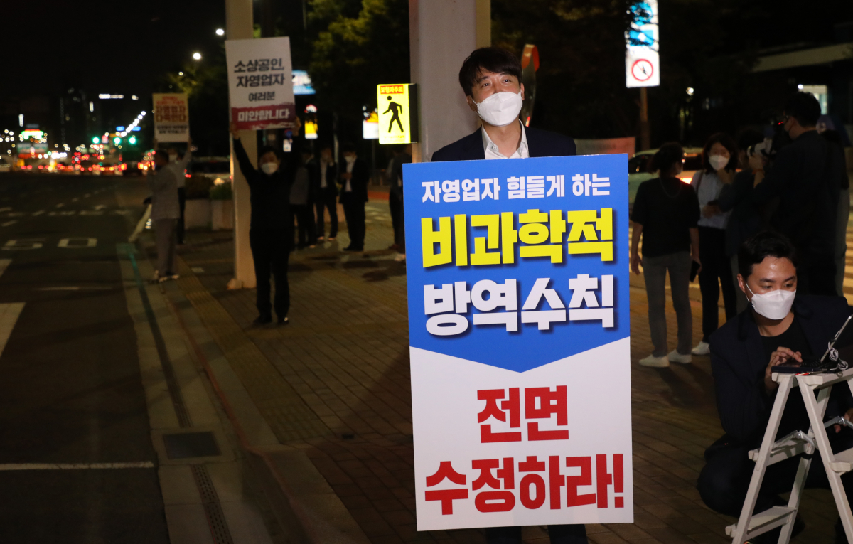 ▲전국자영업자비대위가 코로나19 방역 지침 수정을 요구하며 전국차량시위 중인 9일 새벽 이준석 국민의힘 대표가 여의도에서 방역수칙 수정을 요구하는 일인시위를 하고 있다. 이 대표 뒤는 원희룡, 최재형 대선 경선후보. (연합뉴스)