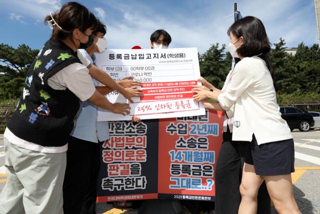 ▲16일 오후 서울 서초구 서울중앙지방법원 앞에서 대학생들이 납부 등록금이 적혀 있는 고지서 피켓에 등록금 인하 등을 촉구하는 스티커를 붙이는 퍼포먼스를 하고 있다.  (뉴시스)
