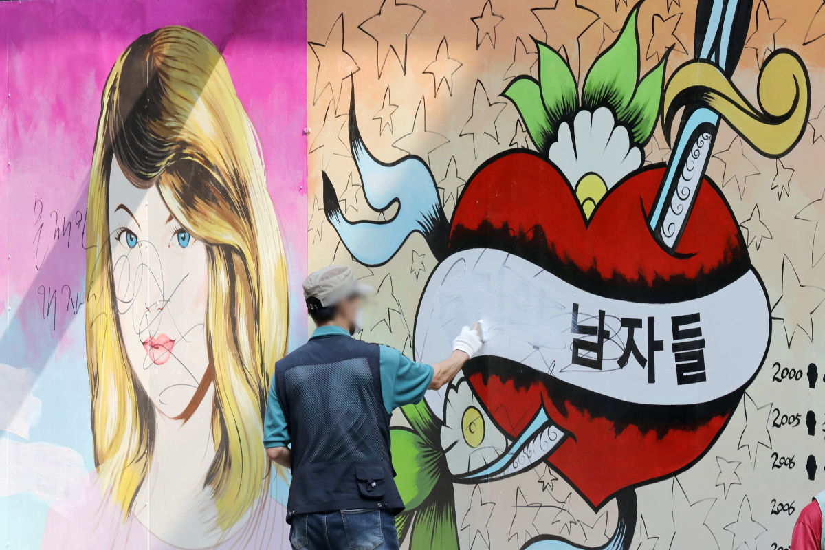 ▲지난 7월 30일 오전 서울 종로구 윤석열 전 검찰총장의 아내 김건희 씨를 비방하는 내용의 벽화가 그려진 서점 외벽에서 서점 관계자가 벽화 속 문구를 지우고 있다. (뉴시스)