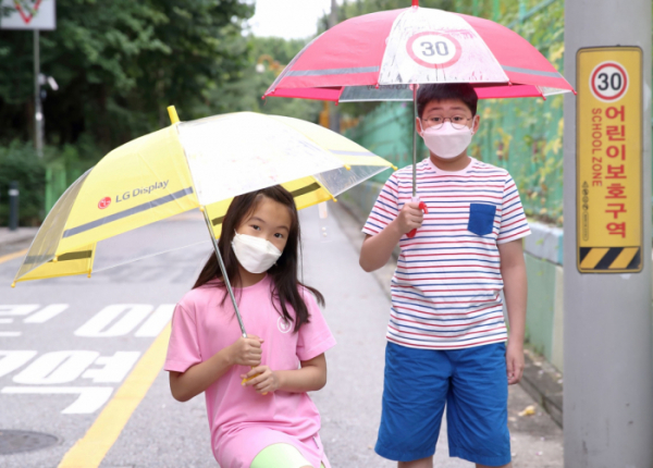 ▲LG디스플레이가 어린이들의 안전을 위해 빗길 교통사고 예방 효과가 높은 '투명 안전 우산' 1만 6,000개를 무료로 배포한다. 어린이들이 LG디스플레이가 준비한 '투명 안전 우산'을 쓰고 있는 모습. (사진제공=LG디스플레이)