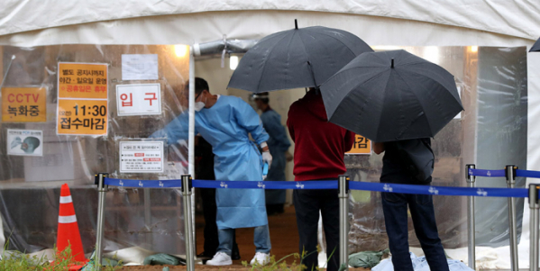 ▲7일 오전 서울 용산역에 마련된 임시선별진료소에서 우산을 쓴 시민들이 코로나19 검사를 받기 위해 길게 줄지어 서 있다. (뉴시스)