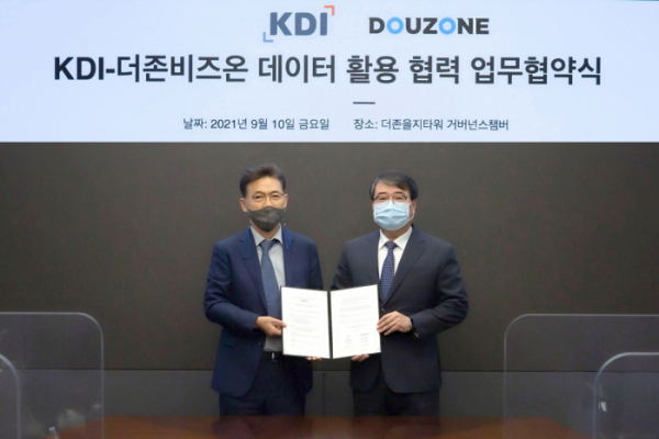 ▲더존비즈온 김용우 대표(오른쪽)와 한국개발연구원 홍장표 원장이 협약서를 교환하고 있다. (사진 제공=더존비즈온)