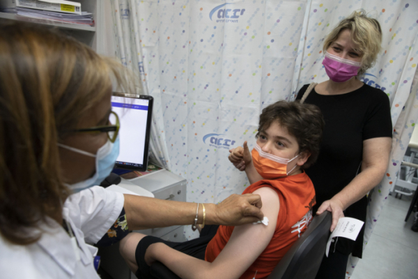 ▲이스라엘 텔아비브 인근 접종소에서 한 어린이가 코로나19 백신 접종하고 있다. 이스라엘은 12~15세 어린이, 청소년을 대상으로 코로나19 백신 접종을 시작했다.  (텔아비브=AP/뉴시스)