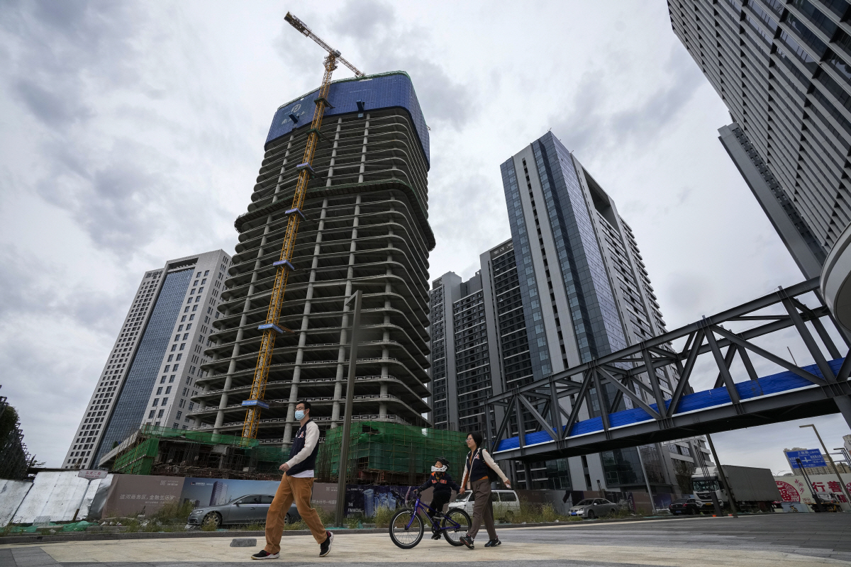 ▲중국 베이징에 위치한 사무실 건물 공사 현장을 4일(현지시간) 사람들이 지나가고 있다. 베이징/AP연합뉴스
