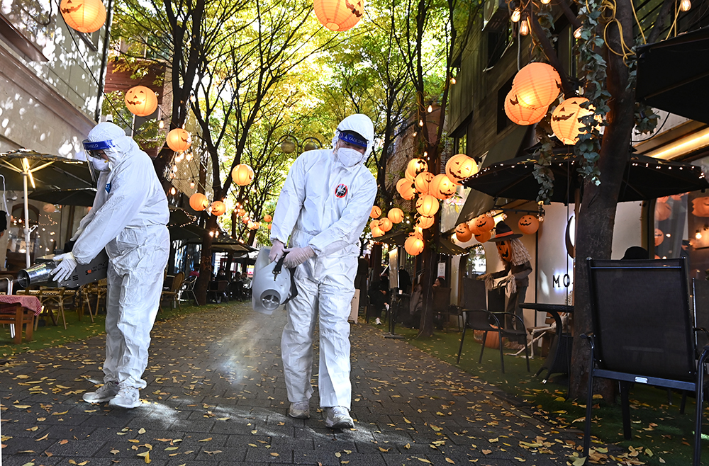 ▲핼러윈데이를 나흘 앞둔 27일 오후 경기도 용인시 보정동 카페거리에서 기흥구보건소 관계자들이 코로나19 예방을 위해 방역소독을 하고 있다. (뉴시스)