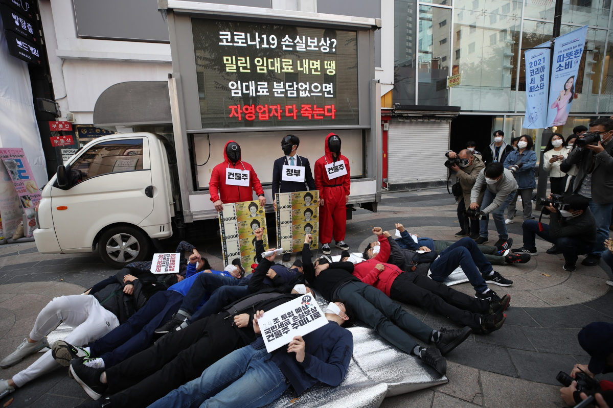 ▲한국중소상인자영업자총연합회, 한국자영업자협의회 등 자영업자 단체 회원들이 27일 오전 서울 중구 명동예술극장 앞에서 자영업자 코로나19 손실보상 집행을 앞두고 임대료 분담 대책을 촉구하는 '코로나19 임대료를 멈춰라' 캠페인 돌입 기자회견을 열고 정부와 건물주 앞에 쓰러진 자영업자를 상징하는 퍼포먼스 하고 있다.  (뉴시스)