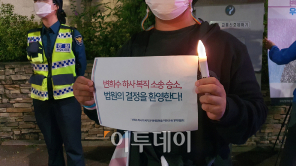 ▲7일 촛불 행진에 참여한 한 시민이 주최 측이 나눠준 '변희수 하사 복직 소송 승소, 법원의 결정을 환영한다!'는 메시지를 들고 있다.  (유혜림 기자 wiseforest@)