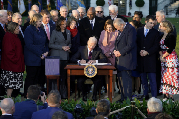▲조 바이든 미국 대통령이 15일(현지시간) 미국 워싱턴D.C. 백악관 잔디밭에서 의원들 사이에서 인프라 법안에 서명하고 있다. 워싱턴D.C./로이터연합뉴스