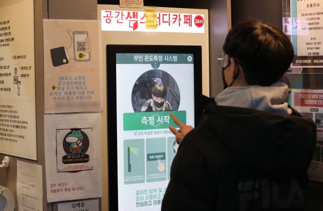 ▲한 스터디카페에서 학생들이 입장 전 무인 온도측정 시스템으로 체온을 측정하고 있다.   (연합뉴스)