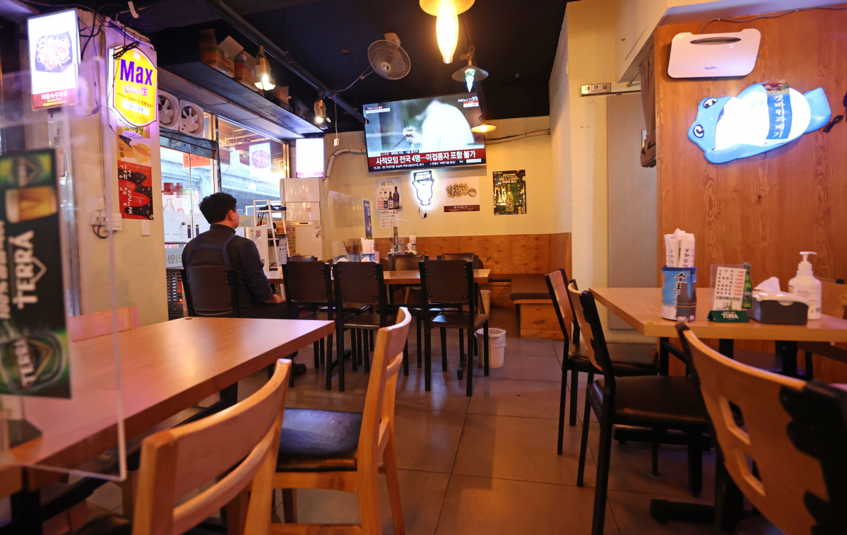 ▲전국 사적 모임 인원 4인 제한을 하루 앞둔 17일 오후 서울의 한 음식점에서 자영업자가 관련 뉴스를 보고 있다. (연합뉴스)