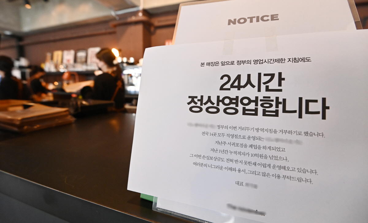 ▲코로나19 확산으로 전국에 강화된 방역 조치가 시행중인 21일 오후 경기도 용인시 한 카페에 정부의 영업 제한 조치를 거부하고 24시간 영업을 한다는 안내문이 붙어있다. (뉴시스)
