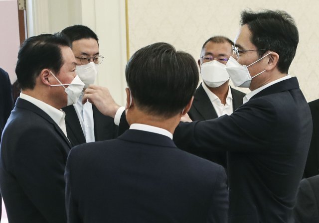 ▲이재용 삼성전자 부회장이 27일 청와대에서 열린 ‘청년희망온(ON)’에 참여한 대기업 대표들과 오찬 간담회 시작 전 최태원 SK 회장의 X자로 엇갈린 마스크 끈을 고쳐주고 있다. (청와대사진기자단)
