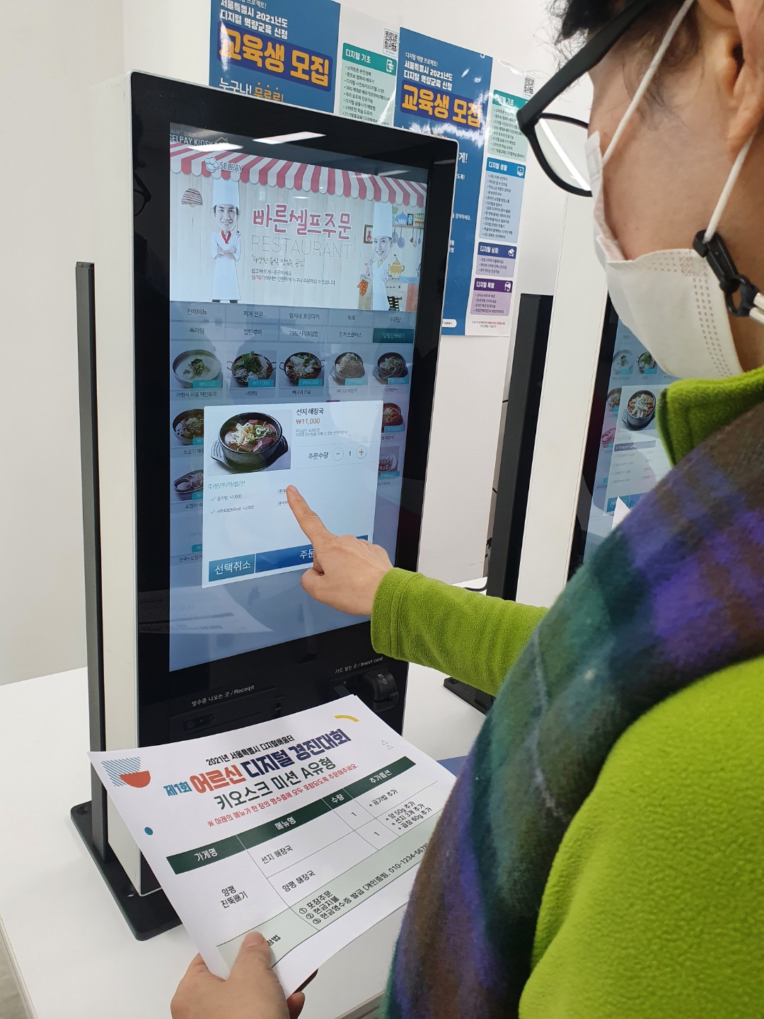 ▲27일 서울 도봉구 창동아우르네에서 박명숙 씨가 실습용 주문서를 보며 키오스크로 주문하고 있다.  (박은평 기자 pepe@)