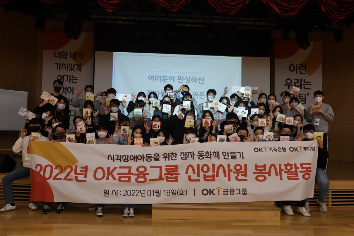▲ OK금융그룹은 지난 18일 자사 신입사원을 대상으로 ‘점자 동화책 만들기’ 봉사활동을 펼쳤다. 사진은 신입사원들이 완성된 점자 동화책을 들고 포즈를 취하고 있다.