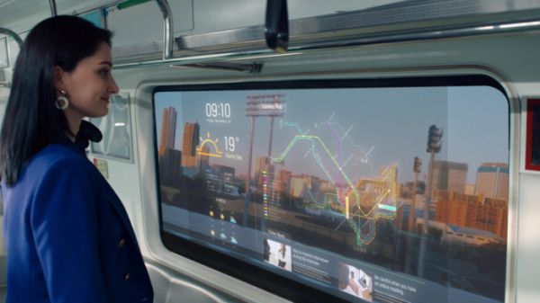 ▲LG디스플레이 모델이 ‘지하철 윈도우용 투명 OLED’를 통해 바깥 풍경을 보는 동시에 운행스케줄, 위치정보, 일기예보나 뉴스와 같은 생활정보를 살펴보고 있는 모습. (사진제공=LG디스플레이)