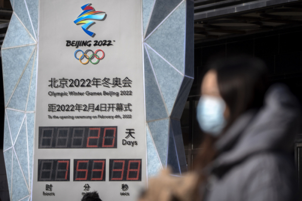 ▲중국 베이징 한 여성이 15일(현지시간) 마스크를 착용한채 2022년 베이징 동계올림픽 개막일을 카운트다운하는 시계 앞을 지나가고 있다.  베이징/AP뉴시스 
