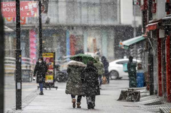 ▲17일 오후 서울 중구 명동거리를 찾은 시민들이 내리는 눈을 맞으며 이동하고 있다.  (뉴시스)