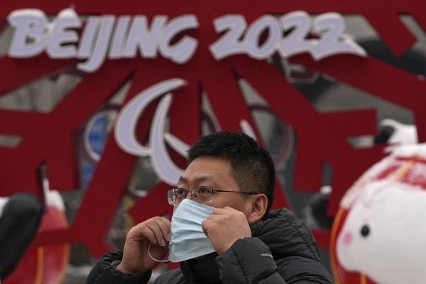 ▲23일 중국 베이징에서 한 남성이 마스크를 쓰고 올림픽 로고 옆을 걸어가고 있다. 베이징/AP연합뉴스
