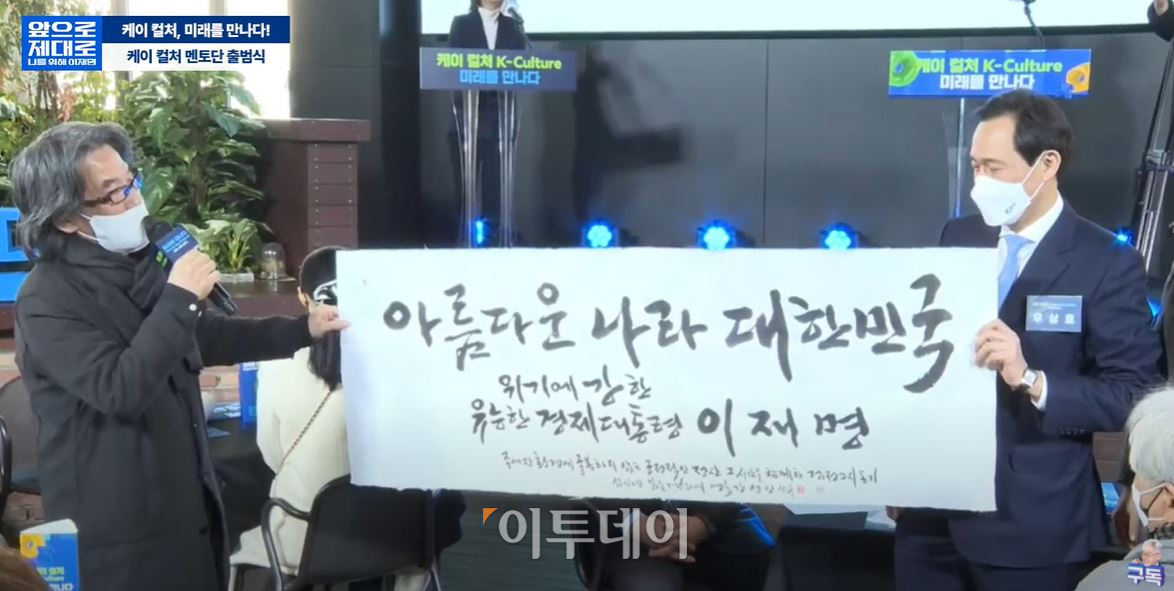 ▲글씨예술가 강병인 씨가 11일 서울 동작구 골든시네마타워에서 열린 '케이(K)컬처 멘토단' 출범식에서 우상호 선대위 총괄본부장에게 '위기에 강한 유능한 경제대통령, 이재명' 글귀를 담은 작품을 전달하고 있다. 강 씨는 아침햇살, 산사춘, 미생, 송곳, 화요, 풀무원 등 대중에 친숙하게 알려진 글씨체를 디자인한 바 있다. (사진=이재명 유튜브 채널 캡쳐)