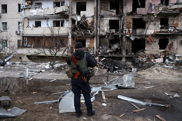▲우크라이나 키예프에서 25일(현지시간) 총기를 휴대한 군인이 포격으로 심하게 파손된 건물 앞에 서 있다. 키예프/로이터연합뉴스 

