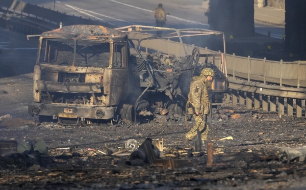 ▲우크라이나 병사가 26일(현지시간) 키예프에서 불에 탄 트럭 주변을 살피고 있다. 키예프/AP뉴시스
