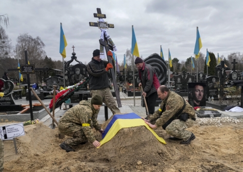 ▲우크라이나 군인들이 5일(현지시간) 우크라이나 키이우의 한 공동묘지에서 러시아군에 의해 숨진 동료의 무덤에 국기를 덮어주고 있다. 키이우/AP뉴시스

